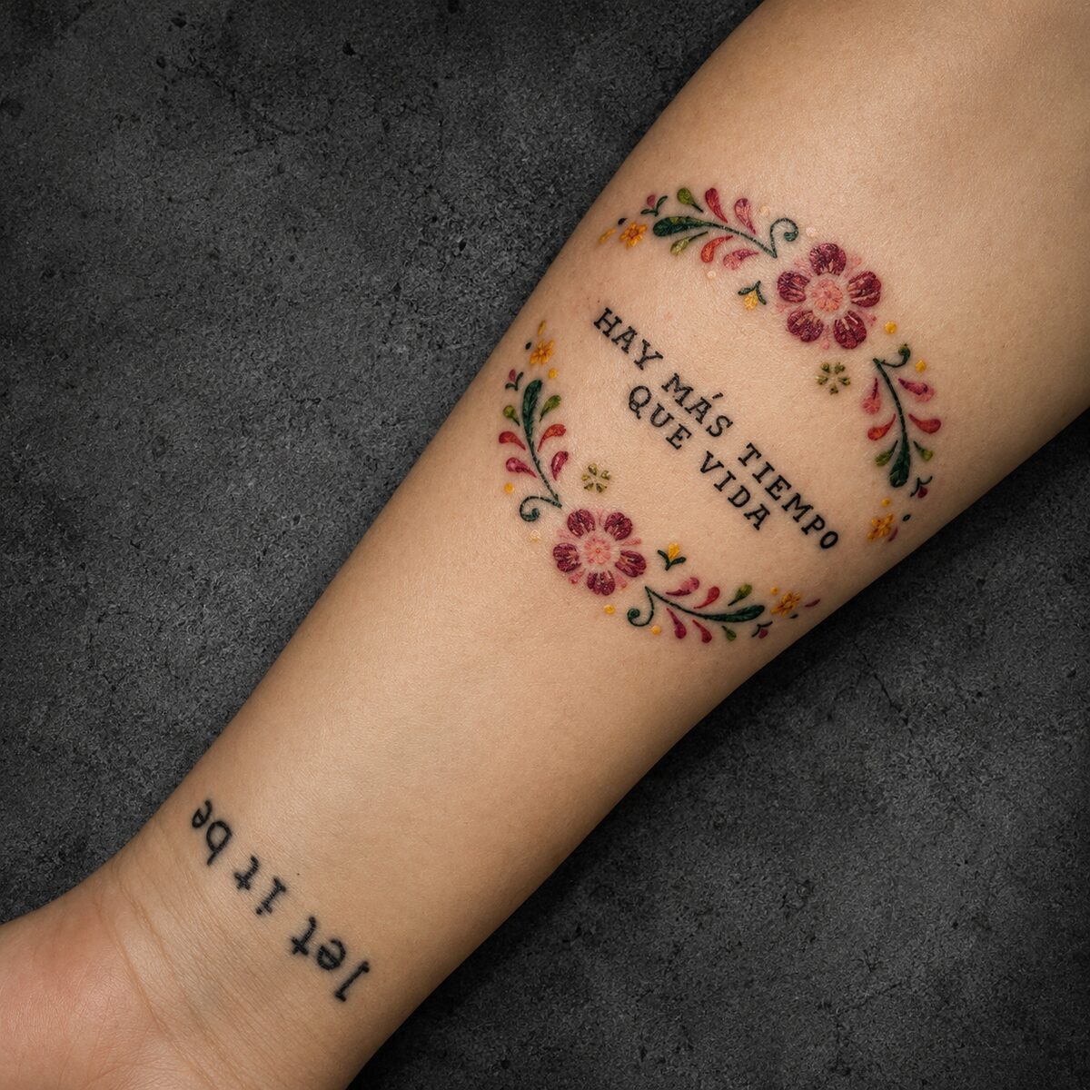 Tatuagem floral colorida com frase, antebraço